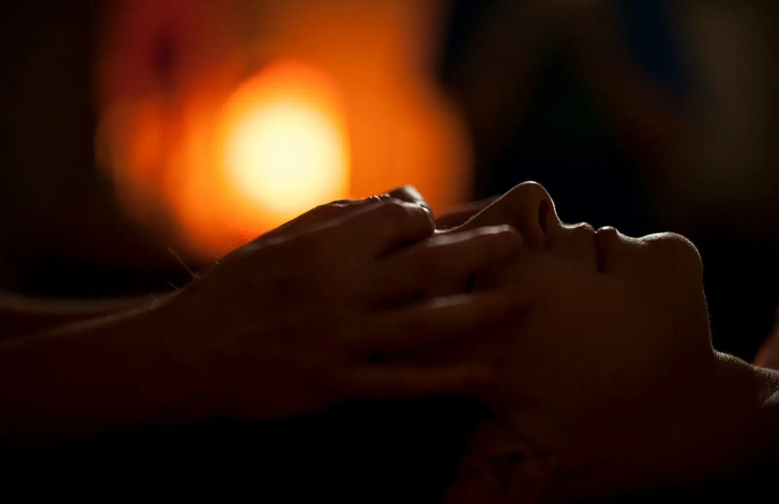 Hands resting gently at a client's head during a Reiki session